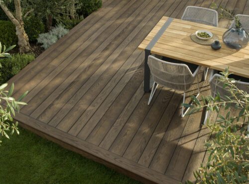 Millboard Enhanced Grain decking in Antique Oak used on a Nashville outdoor living space with a dining table and surrounding greenery.