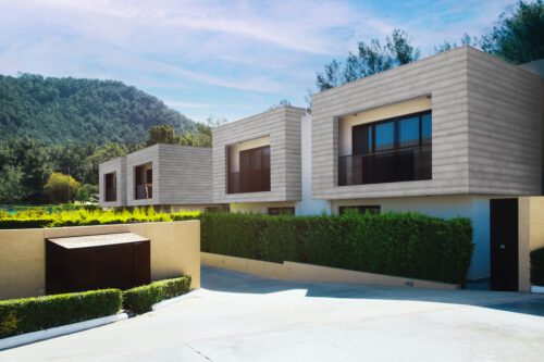 Modern residential homes clad in Millboard Shadow Line composite cladding, featuring clean horizontal lines, a warm wood-tone finish, and a sleek contemporary façade.