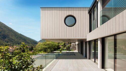 Modern home with Millboard Shadow-Line composite cladding in a limed oak finish, featuring clean architectural lines and a cantilevered second floor with mountain views.