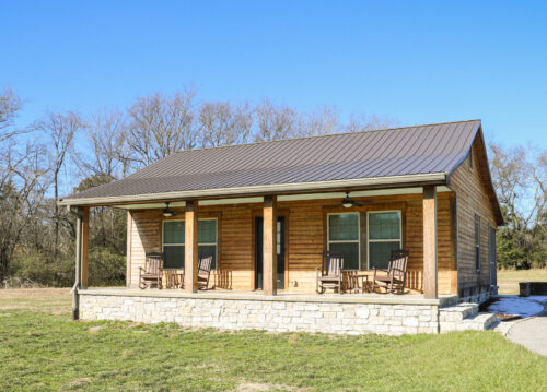 Small cabin with Kebony wood cladding, metal roof, and stone foundation, showcasing a warm natural exterior supplied by TimberTown.