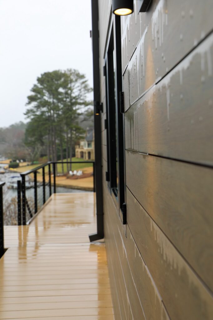 lake-windward-timbertech-deck-trespa-siding- TimberTech deck and aluminum railing detail with lake backdrop.