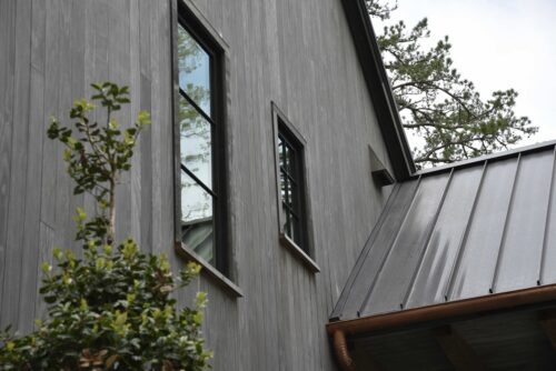 Close-up of Accoya Gray vertical siding with black-framed windows on a modern residential exterior.