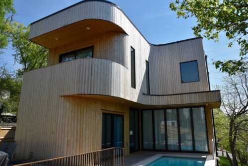 Curved architectural entry wrapped in Thermory knotty pine cladding