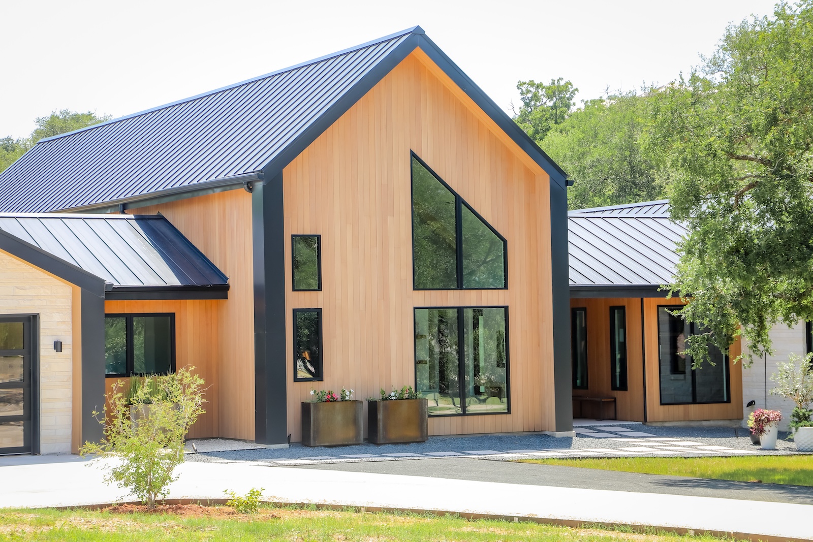 Warm modern exterior featuring Rainier Plank cladding, stone, and expansive glass in Horseshoe Bay.