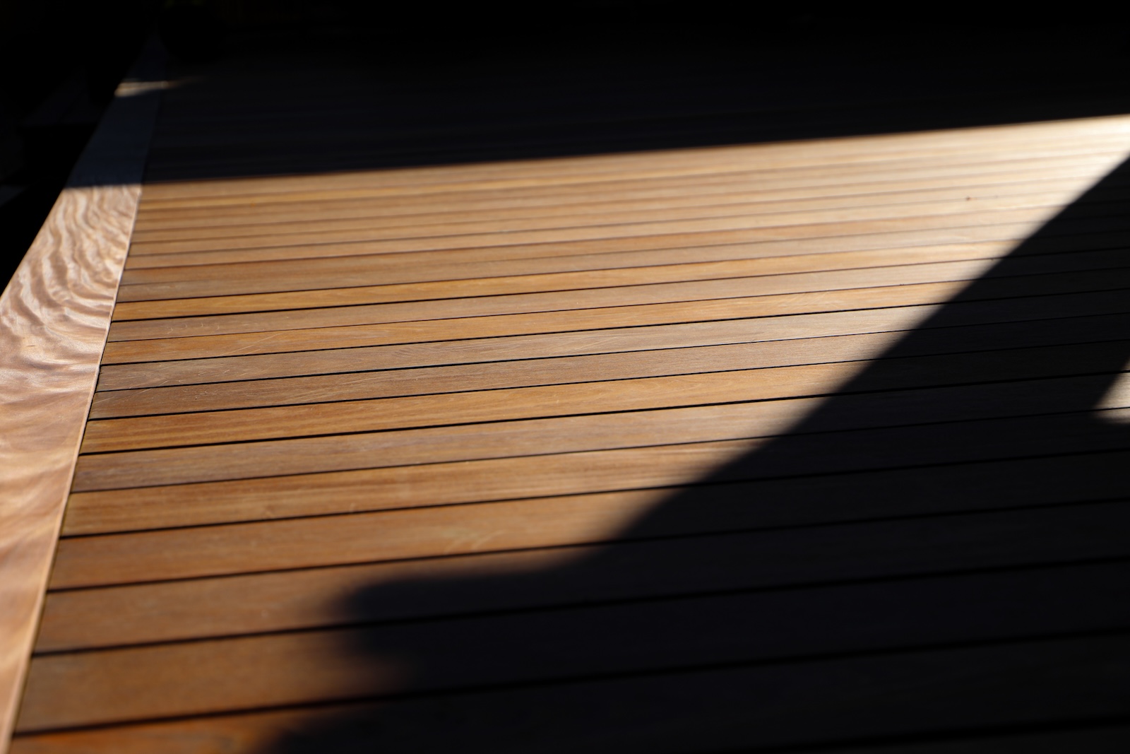 Sunlight filtering through a slatted awning onto the Ipe deck below