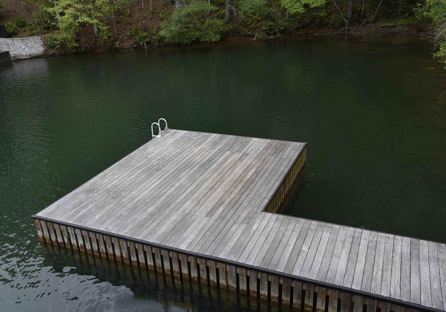 Ipe dock surface surrounded by lake and tree reflections on the lakeside elevation.