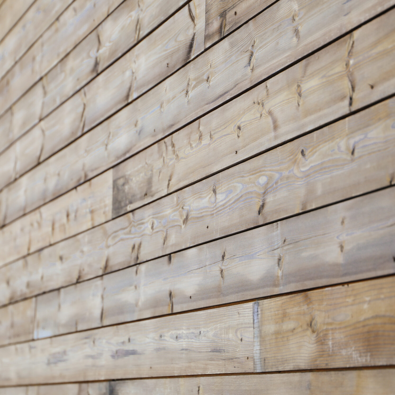 Close-up of Kebony wood cladding showing weathered grain and warm tone variation
